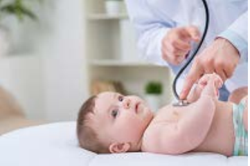 photo of a baby lying on its back with an out of frame doctor using a stethoscope 