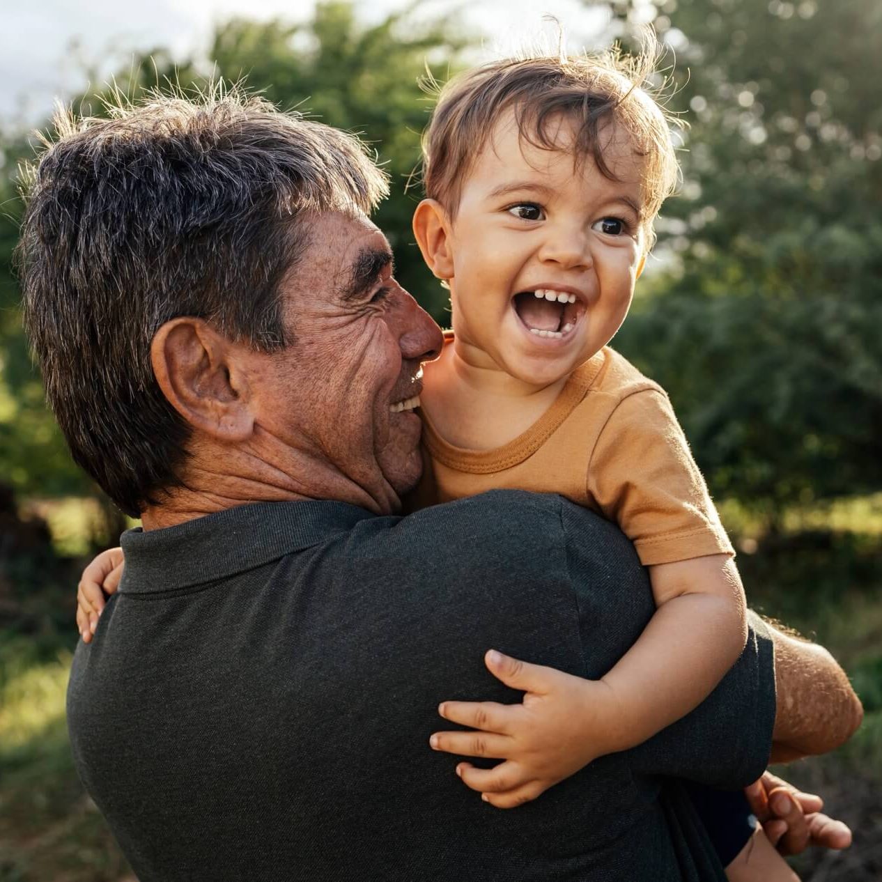 Adult holding a young child, both smiling brightly.