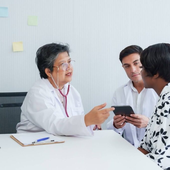 Two doctors explaining something to a patient.